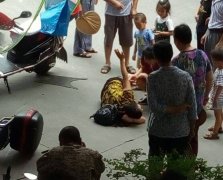 两车相撞女子卷入摩托车底 路人合力将车抬起