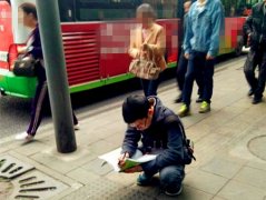 路人匆匆赶公交 男子却蹲地“奋笔疾书”