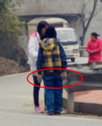 小男孩马路上推母亲  手里还拿着砖头